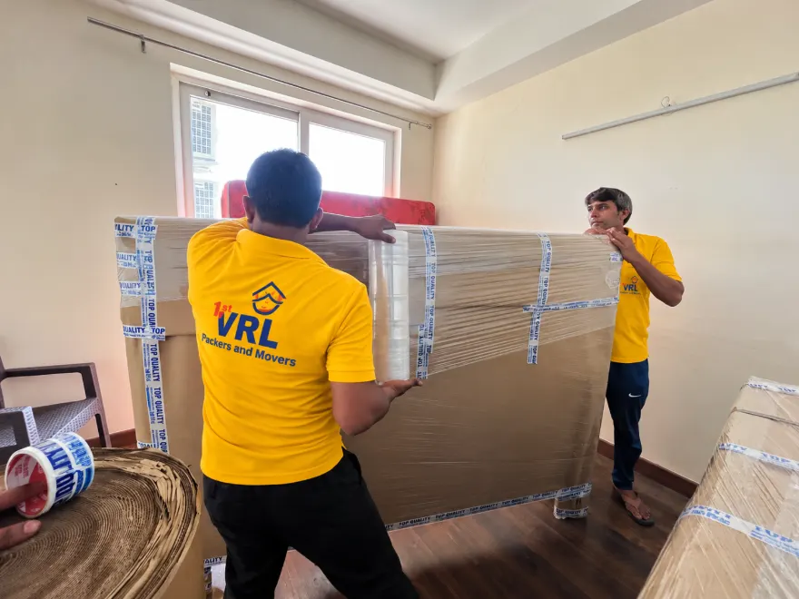 Crew packing a bed headboard with corrugated sheet and stretch film